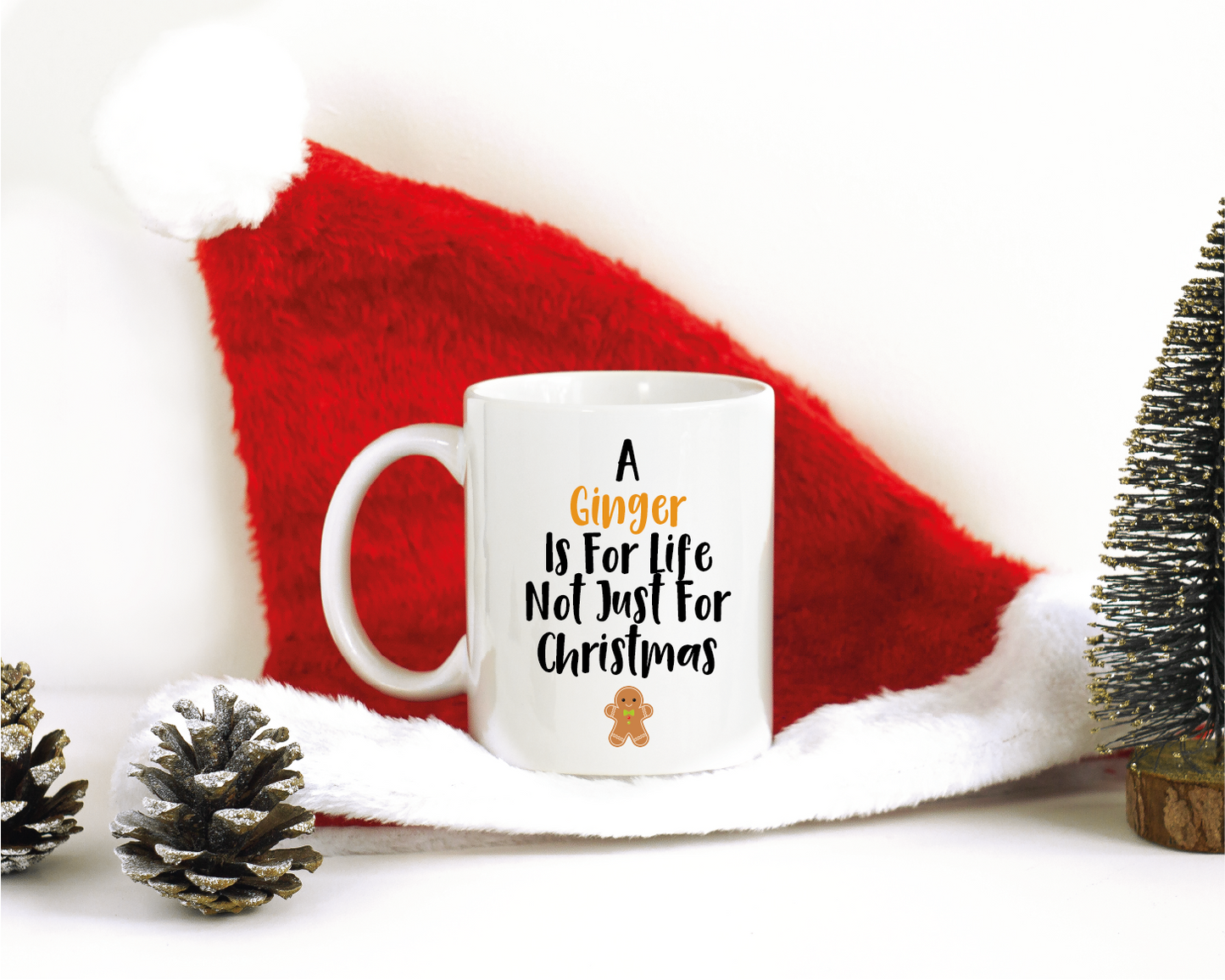 A Christmas themed background with an 11oz white mug which has a design to the front saying 'A Ginger Is For Life Not Just For Christmas' with a picture of a Gingerbread person