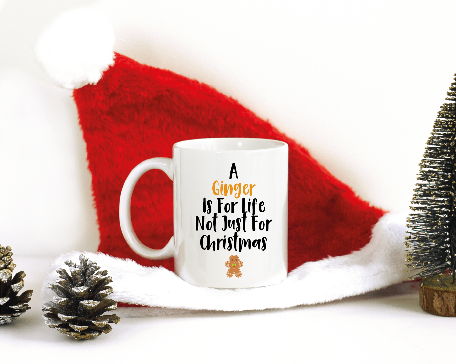 A Christmas themed background with an 11oz white mug which has a design to the front saying 'A Ginger Is For Life Not Just For Christmas' with a picture of a Gingerbread person